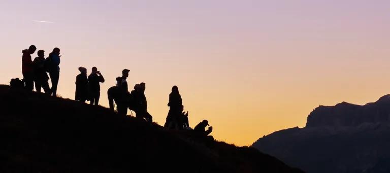 People standing on a hill in sunset. 