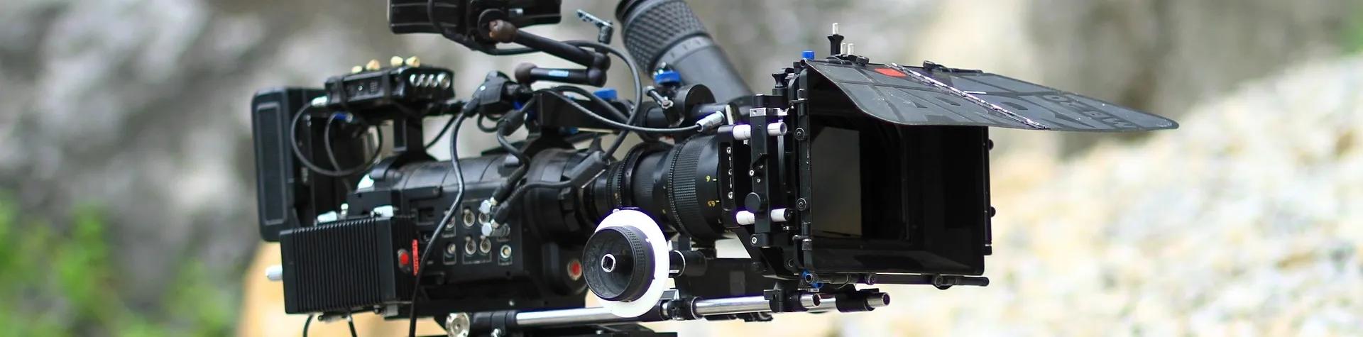 A film camera on a tripod in what looks like a quarry