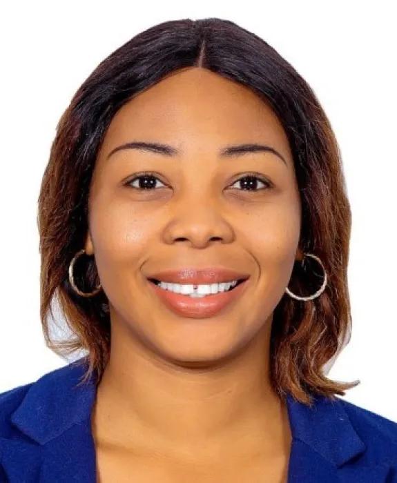 A woman in a blue top smiles at the camera in front of a white background